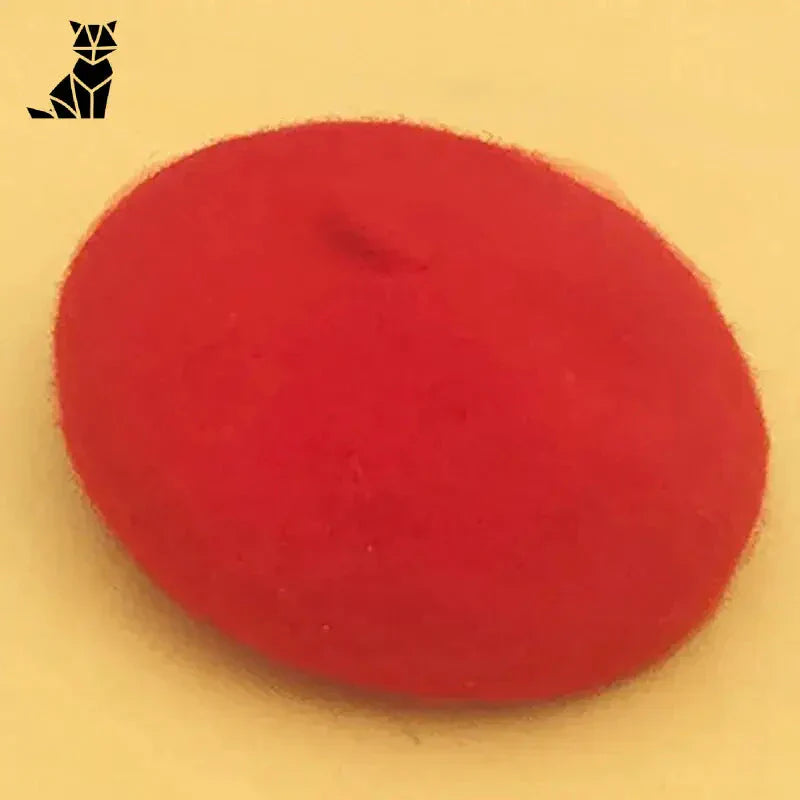 Élégante boule de cire rouge sur surface blanche avec accessoire béret pour chat Chapeau