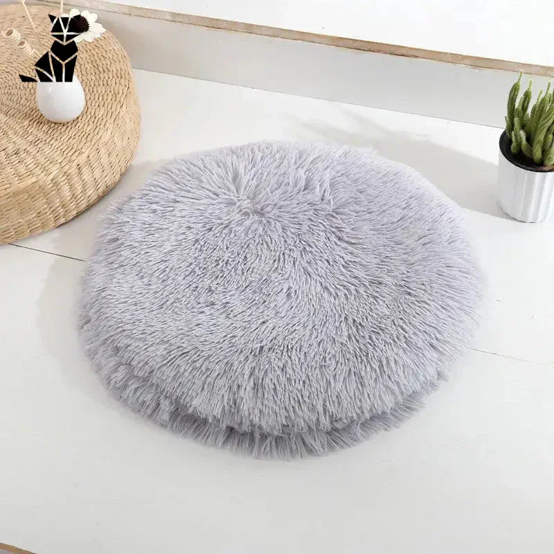 Lit rond en peau de mouton grise sur table blanche pour petits chats et chiens