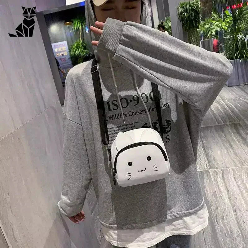 Femme en sweat à capuche gris avec une tête de chat, modélisant le sac à bandoulière Elegant Cartoon Cat